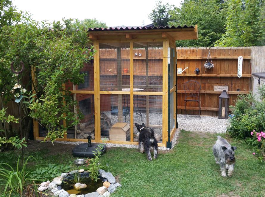 In einem Garten einer Kundin steht die Sonderanfertigung einer Voliere mit Dach.
